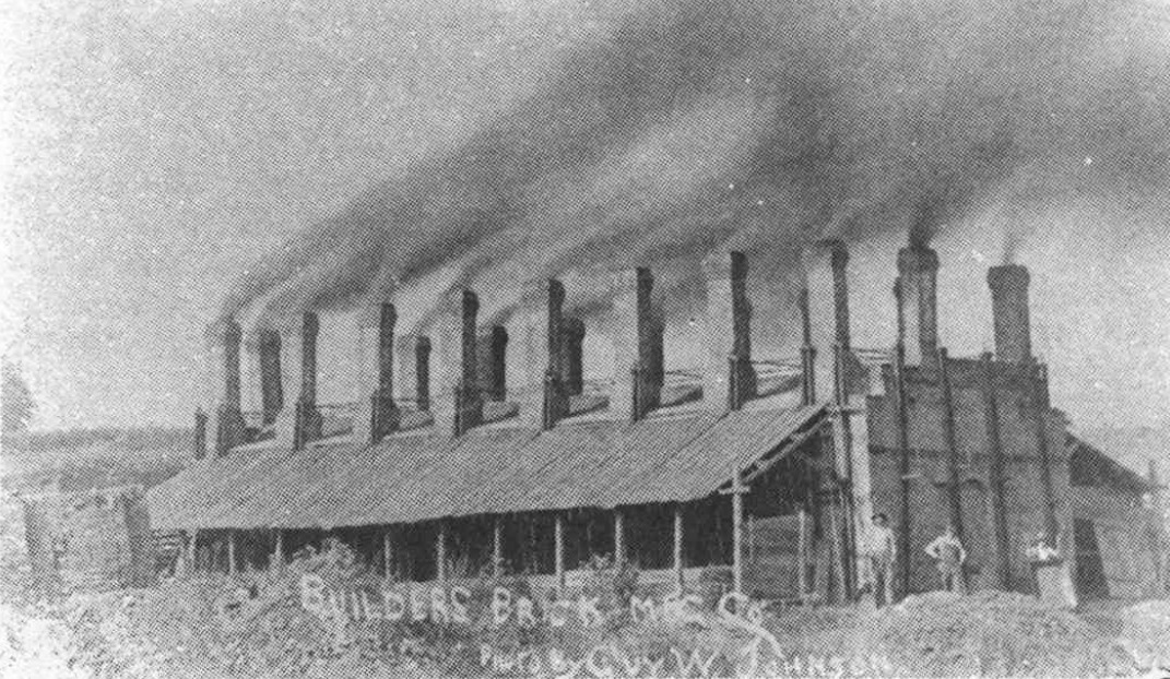Builders Brick Manufacturing Company buildings with a row of smoking chimneys.