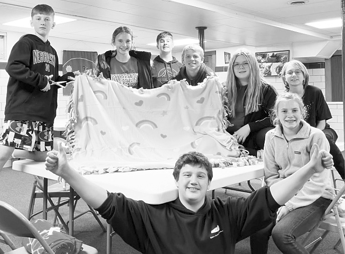 Confirmation students hold a fleece blanket made for a service project in 2022.