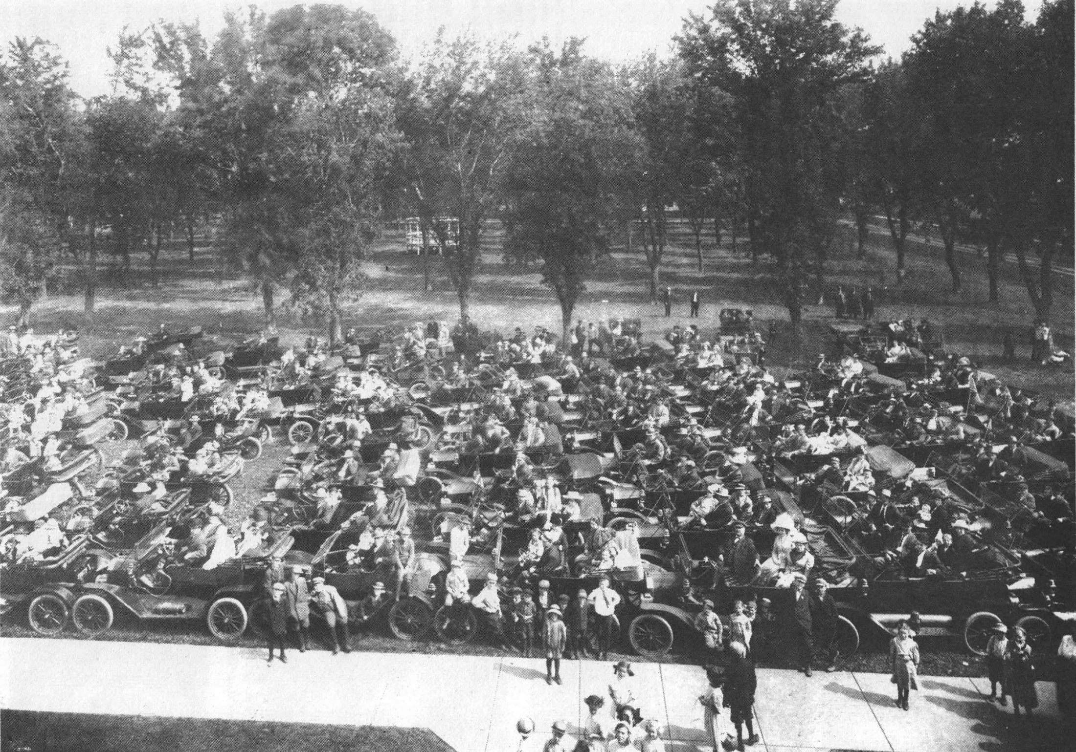 A large gathering of early automobiles and spectators on a tree-lined Hooper street.