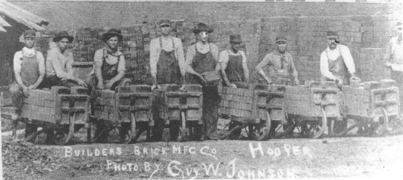 Hooper brickyard workers standing behind brick-loaded carts.