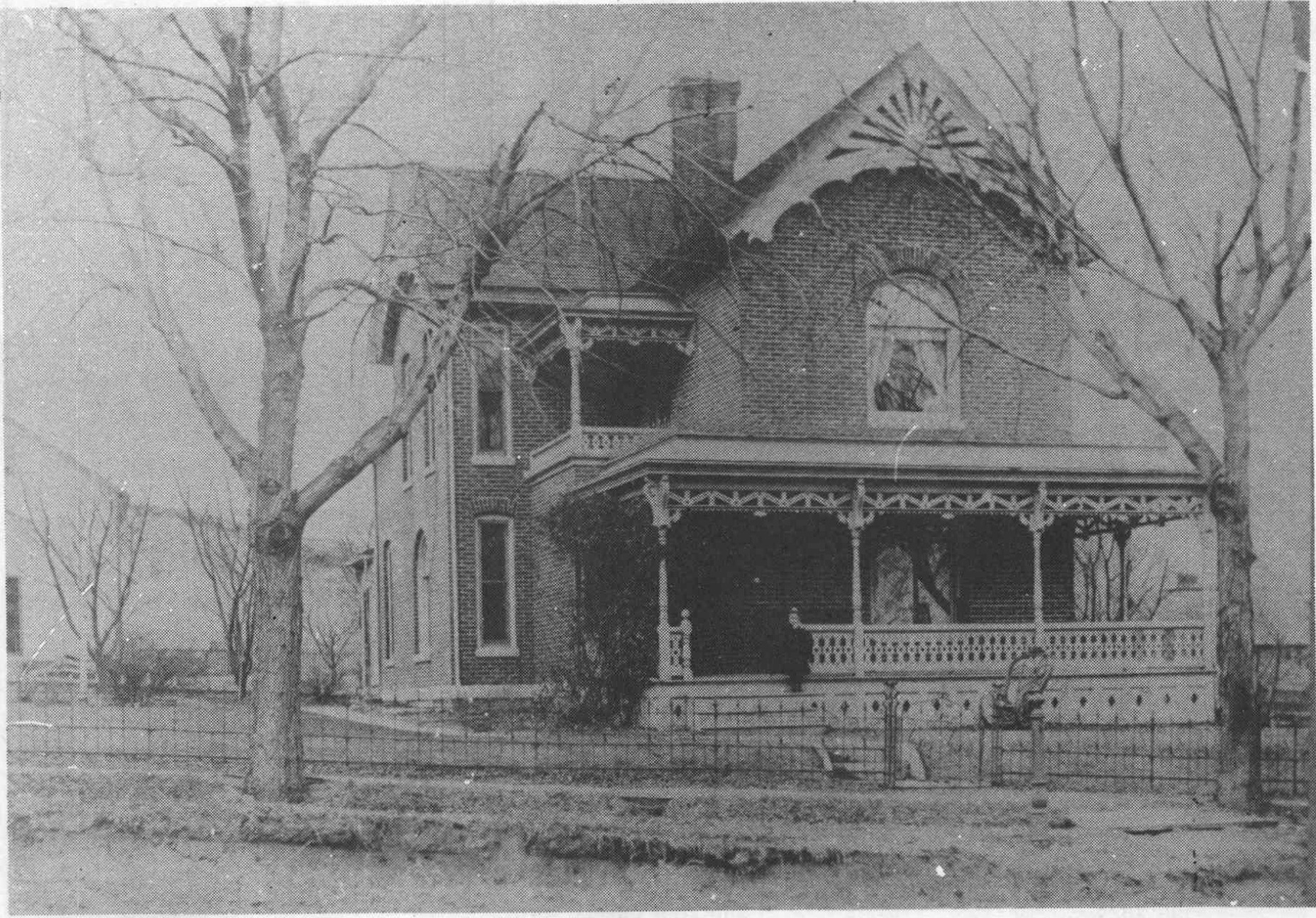 Undated historic photograph of the John F. Heine brick house and its ornate wooden porch.