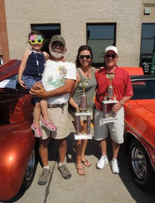 Family with a trophy beside a parade vehicle — details requested, shared by Anne Skidmore